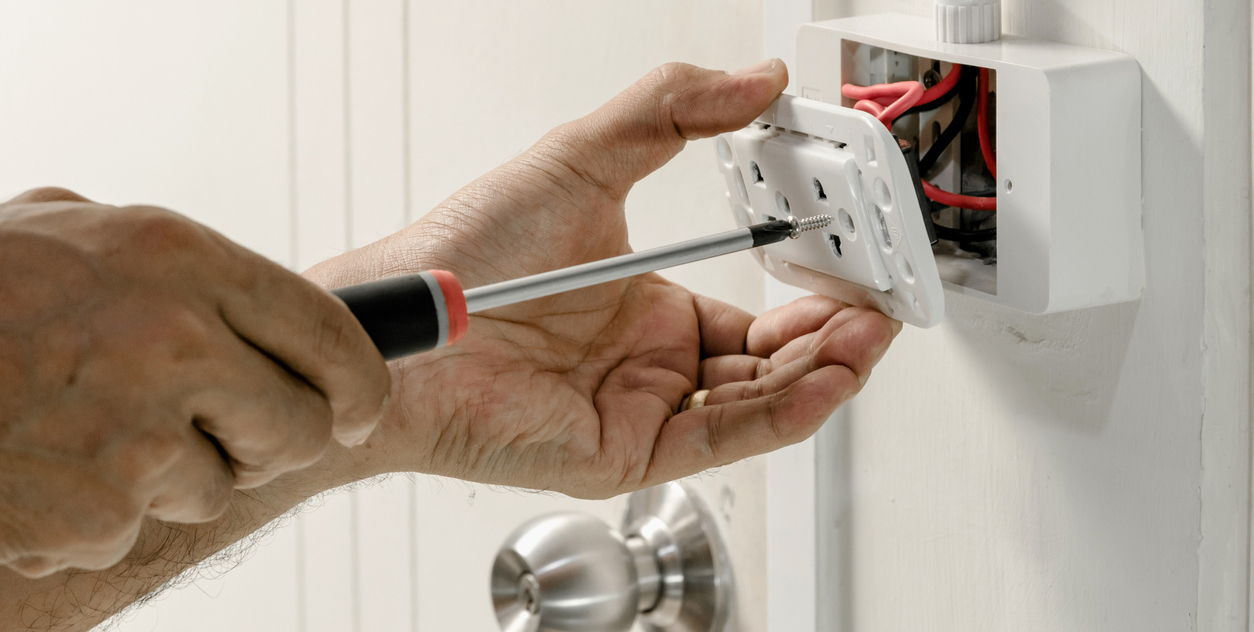 Technician installing a wall power outlet.